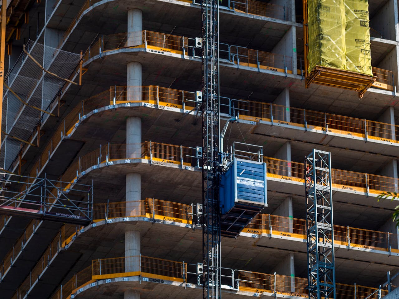 Detailed view of a high-rise building construction featuring a crane and multi-level scaffolding.